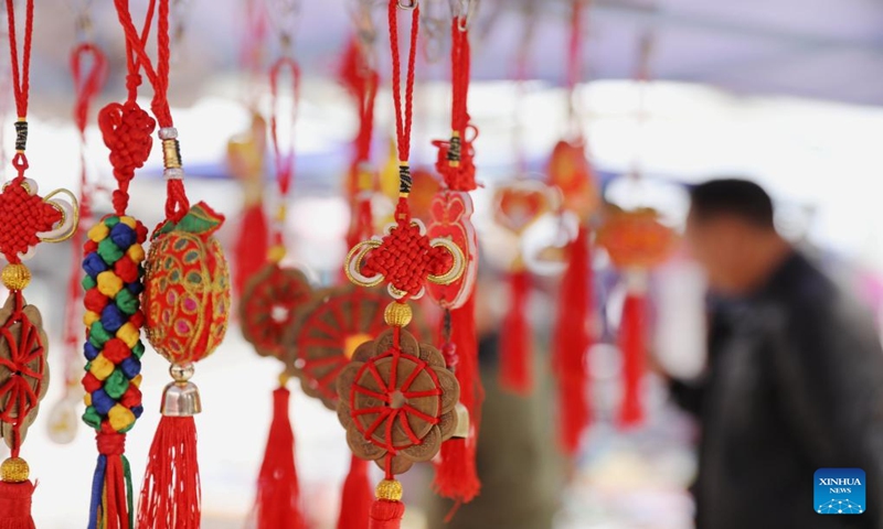 People select decortations for Spring Festival at a market in Qiandongnan Miao and Dong Autonomous Prefecture, southwest China's Guizhou Province, Jan. 13, 2024. China's 2024 Spring Festival holiday will run from Feb. 10 to 17. (Photo by Tai Shengzhi/Xinhua)
