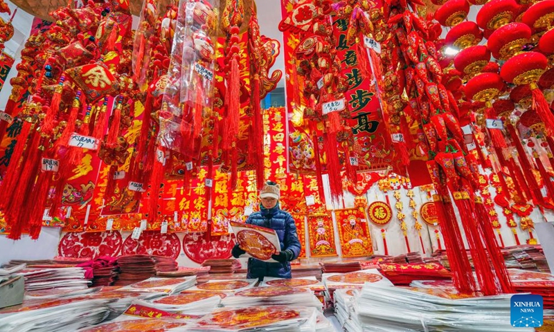 A customer selects decorations for Spring Festival at a market in Yutian County, north China's Hebei Province, Jan. 13, 2024. China's 2024 Spring Festival holiday will run from Feb. 10 to 17. (Photo by Liu Mancang/Xinhua)