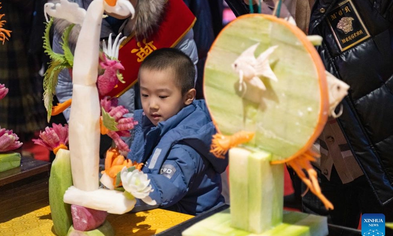 A boy looks at carvings made of vegetables and fruits during a food festival in Harbin, northeast China's Heilongjiang Province, Jan. 20, 2024. (Xinhua/Xie Jianfei)