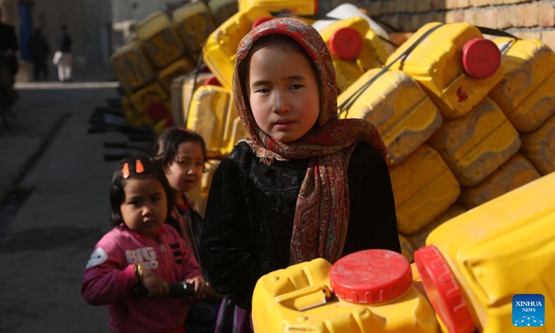 Children stand beside water barrels in Kabul, capital of Afghanistan, Jan. 11, 2024.(Photo: Xinhua)