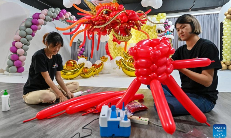 Syndy Tan (R) uses balloons to build a dragon-shaped installation in Kuala Lumpur, Malaysia, on Jan. 18, 2024. In celebration of the upcoming Chinese zodiac Year of the Dragon, Tan, who is good at balloon creations, has used over 600 balloons to build the vivid dragon. (Photo by Chong Voon Chung/Xinhua)