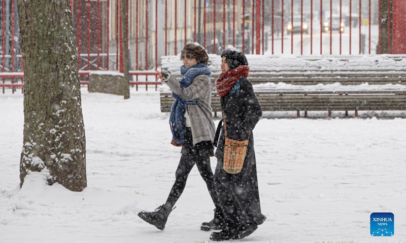 People walk on the snow-covered street in Lille, northern France, Jan. 17, 2024. (Photo by Sebastien Courdji/Xinhua)