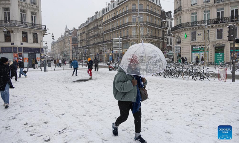 People walk on the snow-covered street in Lille, northern France, Jan. 17, 2024. (Photo by Sebastien Courdji/Xinhua)
