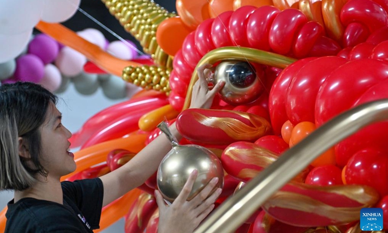 Syndy Tan uses balloons to build a dragon-shaped installation in Kuala Lumpur, Malaysia, on Jan. 18, 2024. In celebration of the upcoming Chinese zodiac Year of the Dragon, Tan, who is good at balloon creations, has used over 600 balloons to build the vivid dragon. (Photo by Chong Voon Chung/Xinhua)