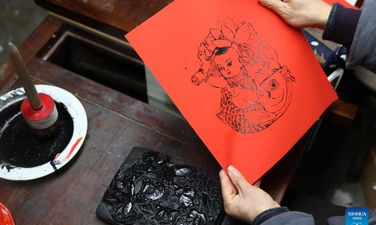 Tong Min looks at a copy of woodcut New Year painting at a studio in Hefei, east China's Anhui Province, Feb 4, 2024. Photo:Xinhua