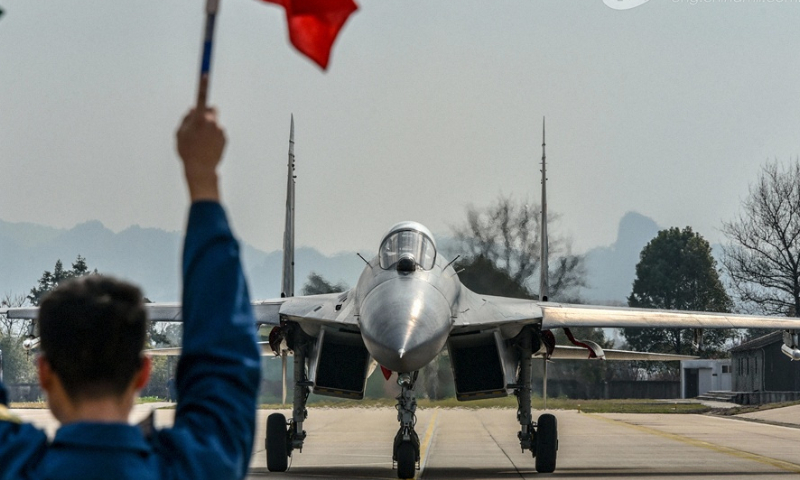 A ground crew member assigned to an aviation brigade of the air force signals a pilot to taxi on the runway after a flight training exercise on February 20, 2024. (eng.chinamil.com.cn/Photo by Fu Gan)