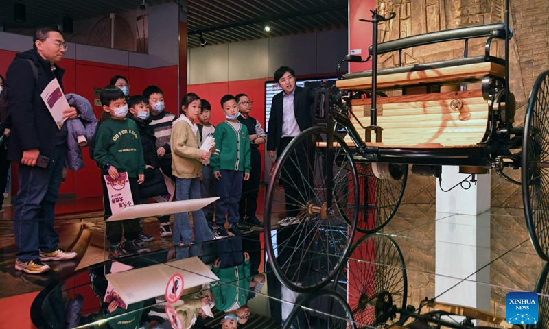 A staff member introduces to children and their parents a vehicle collected by Beijing Auto Museum at the museum in Beijing, capital of China, Jan. 28, 2024. Many children visit Beijing Auto Museum with their parents during this winter vacation to attend popular-science lectures and learn about automobile knowledge. (Xinhua/Ren Chao)