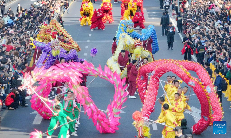 An aerial drone photo taken on Feb. 14, 2024 shows tourists watching a folk art parade in Chongchuan District of Nantong City, east China's Jiangsu Province. More Chinese people nowadays choose to go on a journey during the Spring Festival to experience different cultures and lunar new year atmosphere. (Photo by Xu Congjun/Xinhua)