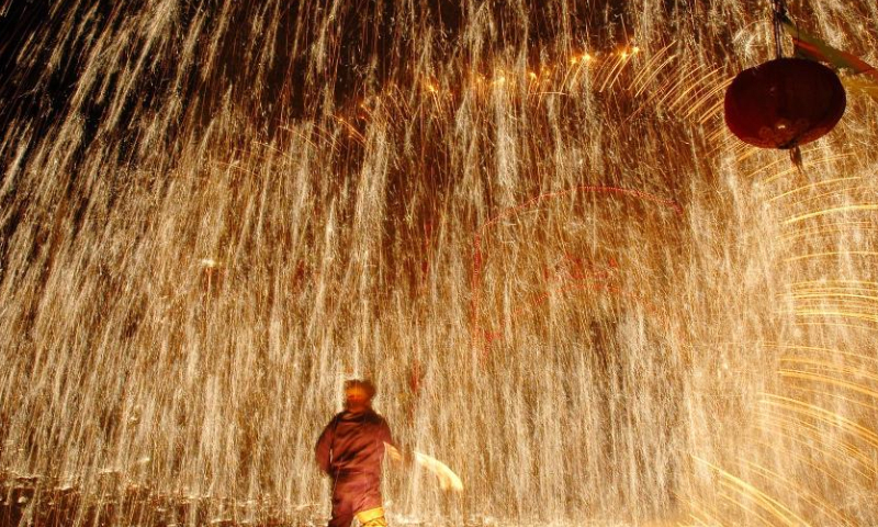 Sparks pour down as the performer sprays molten iron at a Shehuo folk performance in Yuxian County, north China's Hebei Province before the Lantern Festival in 2006.