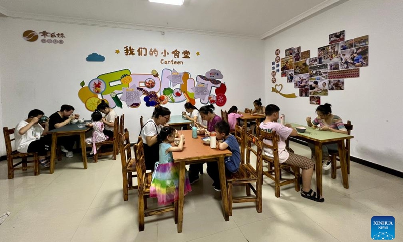 Mothers and their children enjoy a meal together at the Guaiyaomei Tujia ethnic brocade innovative factory's canteen in Zhangjiajie, central China's Hunan Province, July 29, 2023. (Xinhua/Zhang Ge)