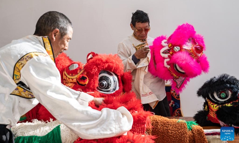 Tengpa Anye (R) cleans a lion dance prop at a primary school in Xobando Town of Lhorong County in Qamdo City, southwest China's Xizang Autonomous Region, Jan. 19, 2024.