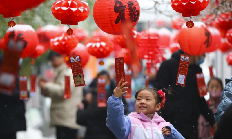 A girl reads a riddle hung from a lantern in Tengzhou City, east China's Shandong Province, Feb. 24, 2024. People across the country celebrated the Lantern Festival on Saturday amid a festive and bustling atmosphere. (Photo by Li Zhijun/Xinhua)