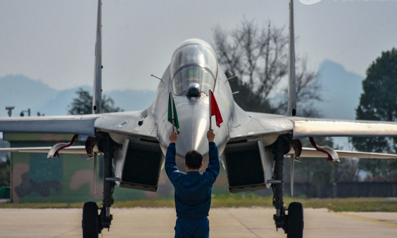 A ground crew member assigned to an aviation brigade of the air force signals a pilot to taxi on the runway after a flight training exercise on February 20, 2024. (eng.chinamil.com.cn/Photo by Fu Gan)