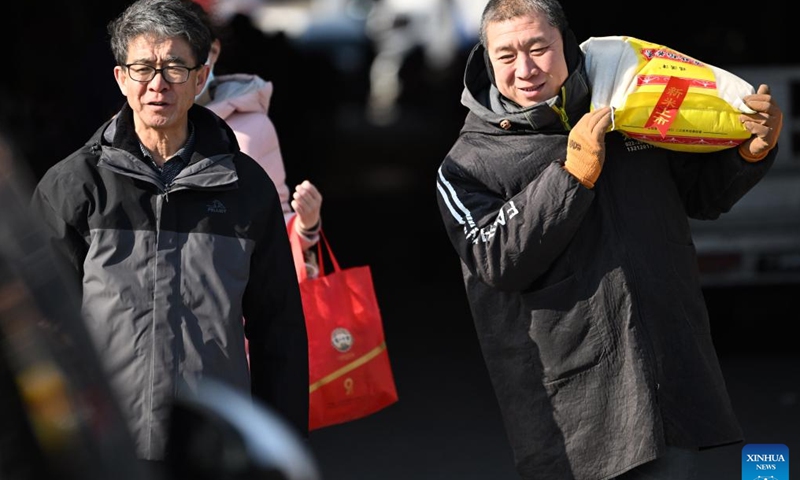 A merchant helps a customer carry a bag of rice during a fair in preparation for the upcoming Spring Festival in north China's Tianjin, Jan. 28, 2024. (Xinhua/Li Ran)