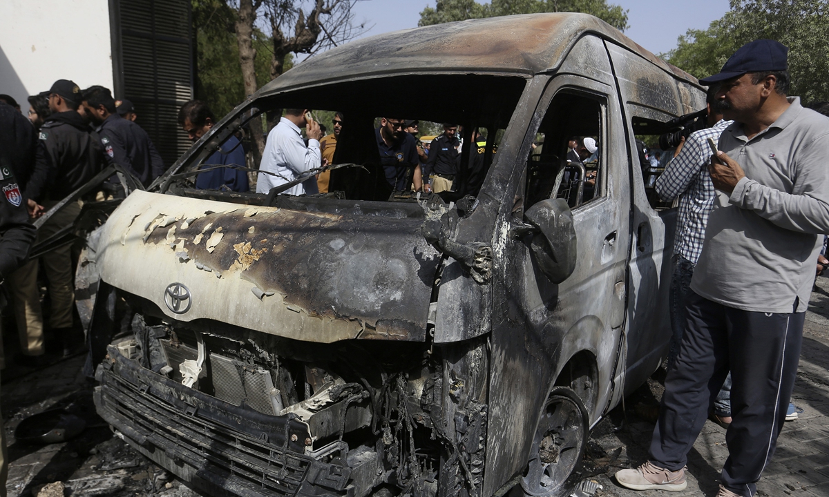Pakistani police officers and investigators examine a burned van after a blast at the entrance of the Confucius Institute at Karachi University on April 26, 2022. The Baloch Liberation Army claimed responsibility for the bombing. Photo: VCG
