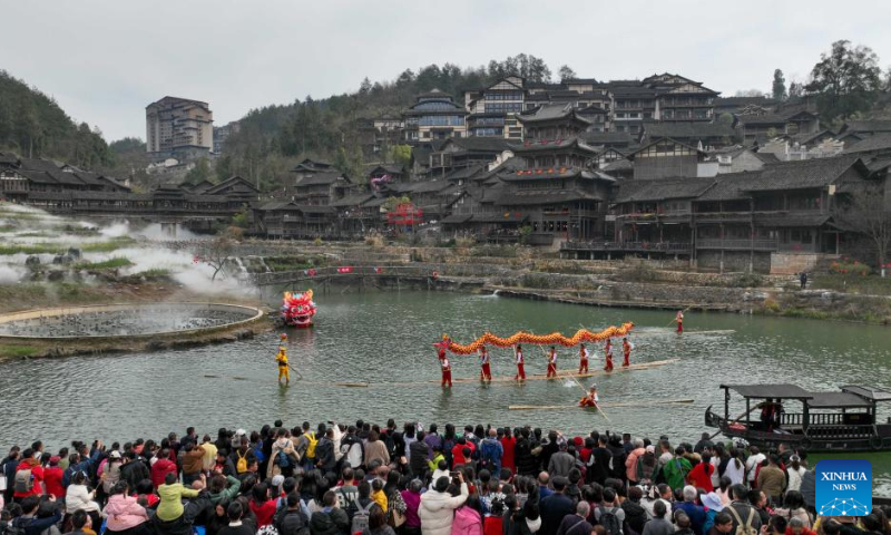 A drone photo taken on Feb. 12, 2024 shows tourists watching a dragon dance performance staged on the water surface in Wujiangzhai scenic spot in Zunyi, southwest China's Guizhou Province. (Photo by Yuan Fuhong/Xinhua)