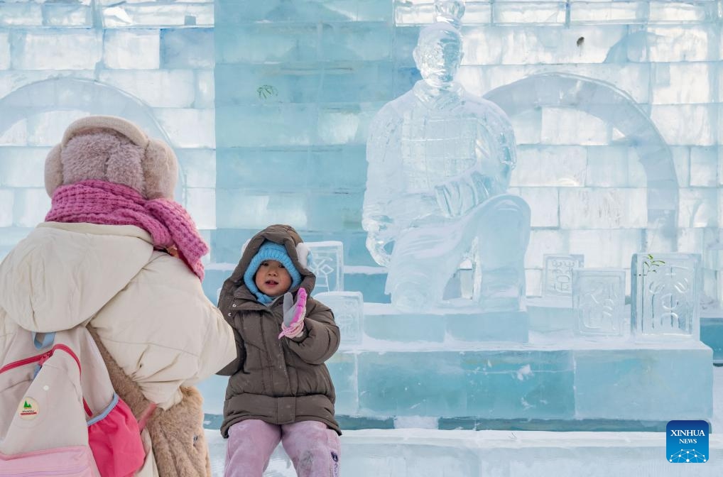 Visitors take photos near an ice sculpture of a Terracotta Warrior in Harbin Ice and Snow World in Harbin, northeast China's Heilongjiang Province, Jan. 23, 2024. As a group of AI-generated images of ice sculptures of Terracotta Warriors went viral on the internet, artists created a series of ice sculptures of Terracotta Warriors at Harbin Ice and Snow World to attract visitors.(Photo: Xinhua)