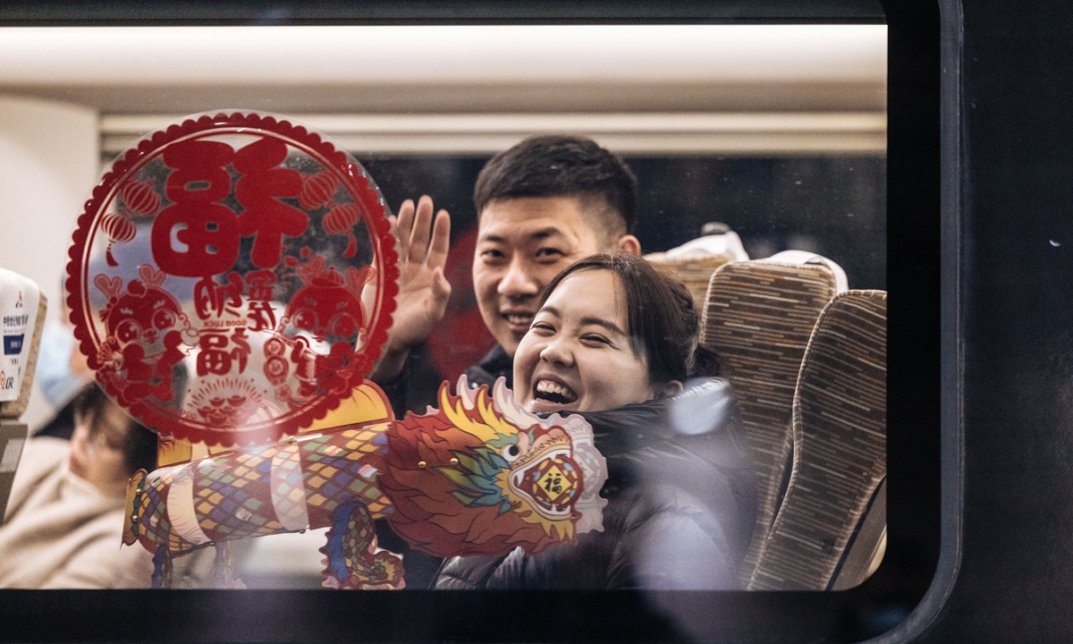 Passengers smile and wave goodbye on a high speed train departing from Beijing West Railway station on January 26, 2024. The train is decorated with dragon-shaped characters as 2024 marks the Year of the Dragon in the Chinese calendar. China's <em>chunyun</em>, or Spring Festival travel rush, the world's largest annual human migration, begins on January 26, 2024. The 40-day <em>chunyun</em> is expected to see a new record of 9 billion passenger trips. Photos: Li Hao/GT