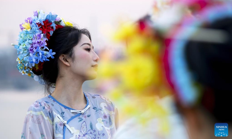 A tourist in a flowery headwear poses for photos at Xunpu Village of Quanzhou City, southeast China's Fujian Province, Jan. 26, 2024.(Xinhua/Wei Peiquan)