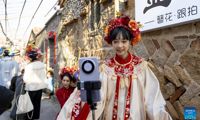 A girl shows her flowery headwear via livestream at Xunpu Village of Quanzhou City, southeast China's Fujian Province, Jan. 26, 2024.(Xinhua/Wei Peiquan)