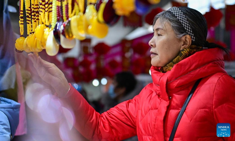 A person selects products during a fair in preparation for the upcoming Spring Festival at the Xinjiang International Convention and Exhibition Center in Urumqi, northwest China's Xinjiang Uygur Autonomous Region, Jan. 27, 2024. (Xinhua/Ding Lei)