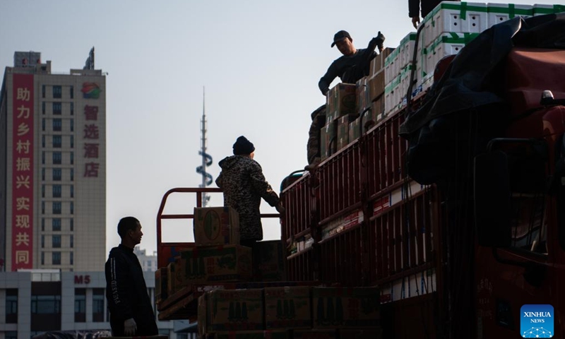 People upload agricultural products onto a truck at an agricultural trade center in Xiaogan, central China's Hubei Province, Jan. 27, 2024. The agricultural trade center, which houses nearly 3,000 dealers of fruits, vegetables, aquatic and frozen products, has taken extra measures to ensure its supply for the upcoming Spring Festival holiday. (Xinhua/Wu Zhizun)