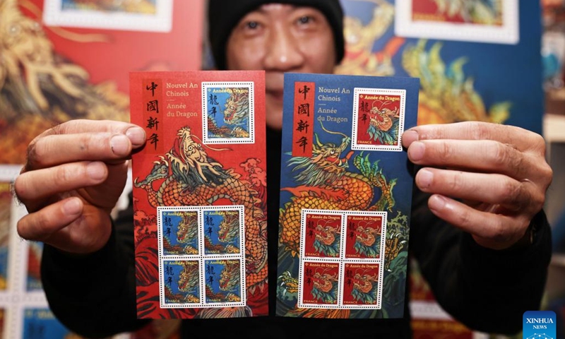 Chen Jianghong, a French artist of Chinese origin who designed a pair of stamps to celebrate the upcoming Chinese Lunar New Year, signs for a philatelist in Paris, France, Jan. 26, 2024. France's La Poste Group unveiled a pair of stamps on Friday to celebrate the upcoming Chinese Lunar New Year, the Year of the Dragon.(Xinhua/Gao Jing)