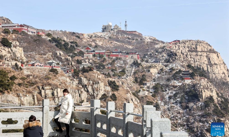 A tourist poses for photo at the Mount Tai scenic area in east China's Shandong Province, Jan. 26, 2024. With its natural and cultural values well interconnected, Mount Tai was listed as a World Cultural and Natural Heritage site by UNESCO in 1987, the first ever in China. In 2023, the Mount Tai scenic area received over 8.61 million visitors, a new record over the years. (Xinhua/Zhu Zheng)