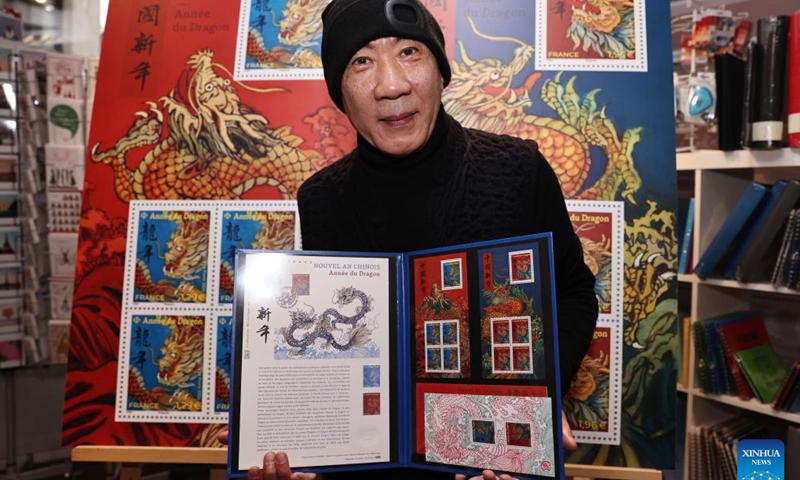 Chen Jianghong, a French artist of Chinese origin who designed a pair of stamps to celebrate the upcoming Chinese Lunar New Year, signs for a philatelist in Paris, France, Jan. 26, 2024. France's La Poste Group unveiled a pair of stamps on Friday to celebrate the upcoming Chinese Lunar New Year, the Year of the Dragon.(Xinhua/Gao Jing)
