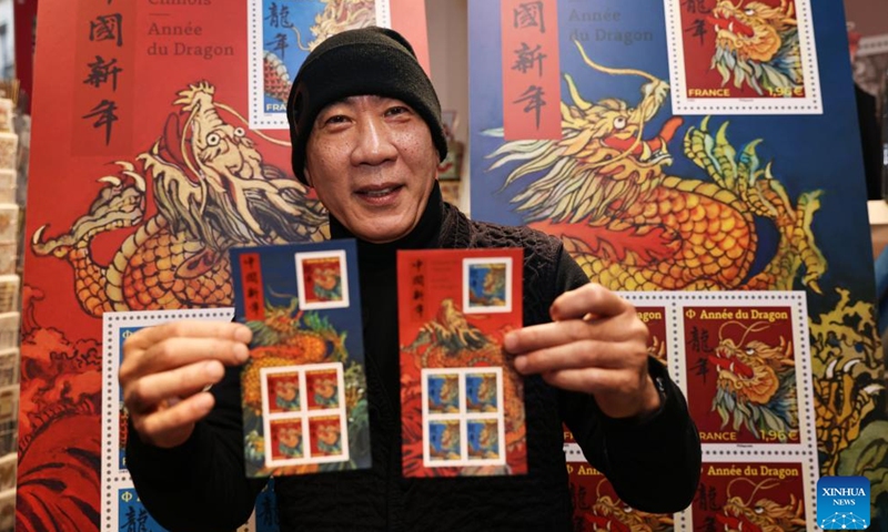 Chen Jianghong, a French artist of Chinese origin who designed a pair of stamps to celebrate the upcoming Chinese Lunar New Year, signs for a philatelist in Paris, France, Jan. 26, 2024. France's La Poste Group unveiled a pair of stamps on Friday to celebrate the upcoming Chinese Lunar New Year, the Year of the Dragon.(Xinhua/Gao Jing)