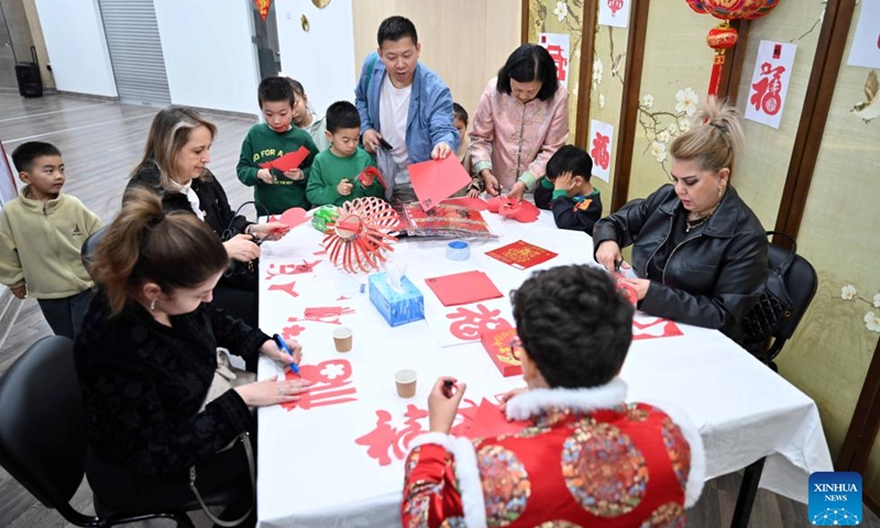 People experience Chinese paper-cutting during a culture event at Kuwait Chinese Cultural Center in Hawalli Governorate, Kuwait, Jan. 25, 2024. A culture event for the upcoming Chinese Spring Festival was held here Thursday, with more than 100 guests gathering to taste traditional food and experience Chinese ink painting, calligraphy, paper-cutting and tea art. (Photo by Asad/Xinhua)