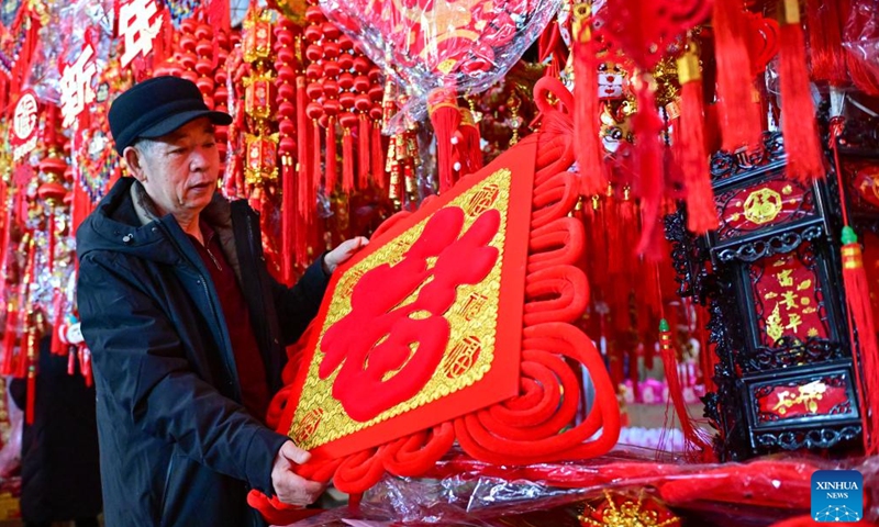 A person selects products during a fair in preparation for the upcoming Spring Festival at the Xinjiang International Convention and Exhibition Center in Urumqi, northwest China's Xinjiang Uygur Autonomous Region, Jan. 27, 2024. (Xinhua/Ding Lei)