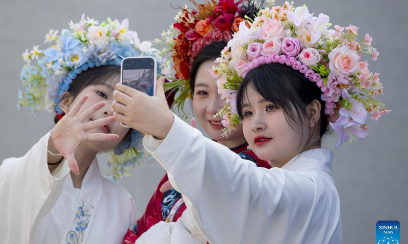 Tourists wearing flowery headwear take selfies at Xunpu Village of Quanzhou City, southeast China's Fujian Province, Jan. 26, 2024.(Xinhua/Wei Peiquan)