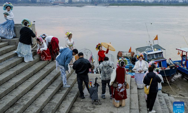 Tourists wearing flowery headwear pose for photos at Xunpu Village of Quanzhou City, southeast China's Fujian Province, Jan. 26, 2024.(Xinhua/Wei Peiquan)