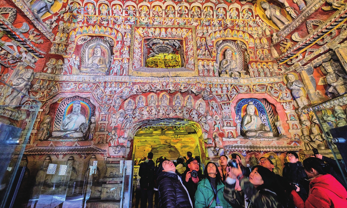 Visitors in a cave of the Yungang Grottoes Photo:VCG