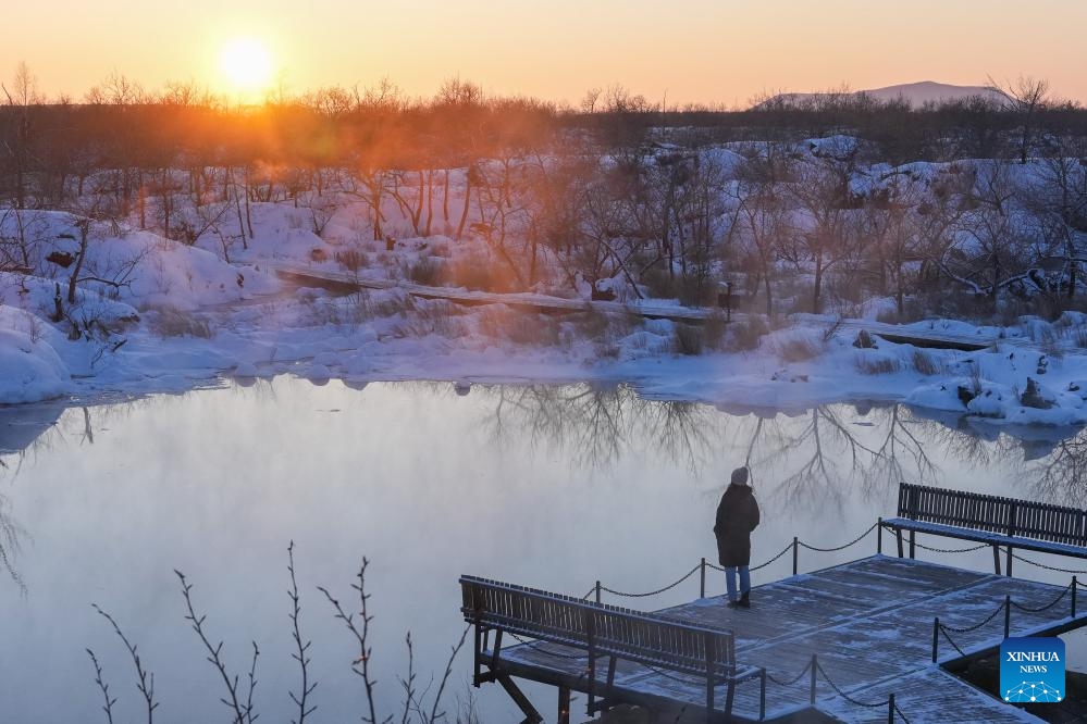 A visitor enjoys the snow scenery of the Wudalianchi Geopark in Heihe, northeast China's Heilongjiang Province, on Jan. 29, 2024. The Wudalianchi Geopark features 14 volcanoes and five major volcanic barrier lakes. The geopark boasts a complete set of volcanic landforms, making it a natural volcano museum.(Photo: Xinhua)