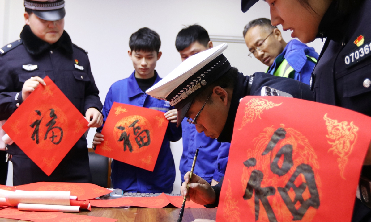 Police officers in Wuhu, East China's Anhui Province, write Chinese character fu (fortune in English) for migrant workers on January 30, 2024, as a blessing for the upcoming Spring Festival. Photo: VCG