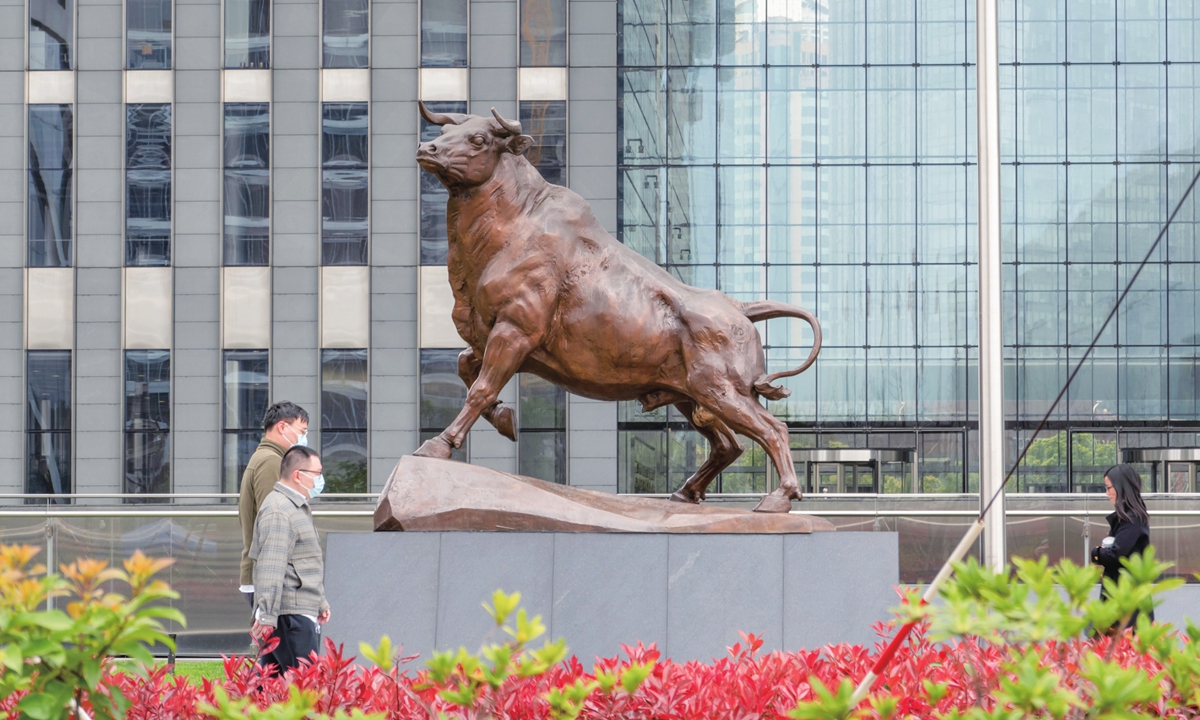 Two men pass the bronze bull at the Shanghai Stock Exchange. 