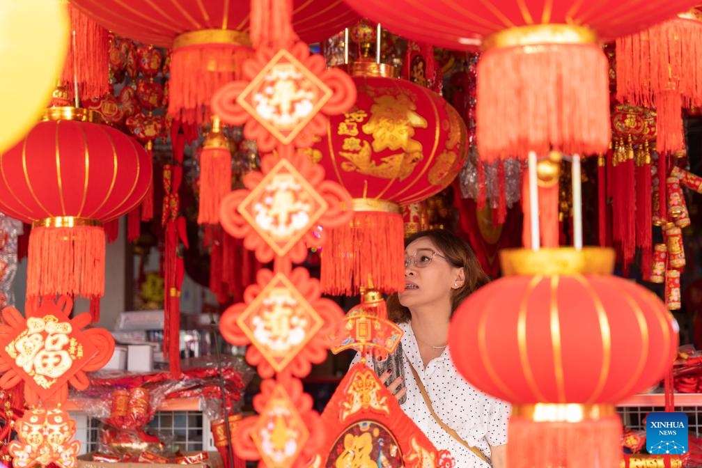 A customer selects Spring Festival decorations at a local market in Vientiane, capital of Laos, Feb. 1, 2024.(Photo: Xinhua)