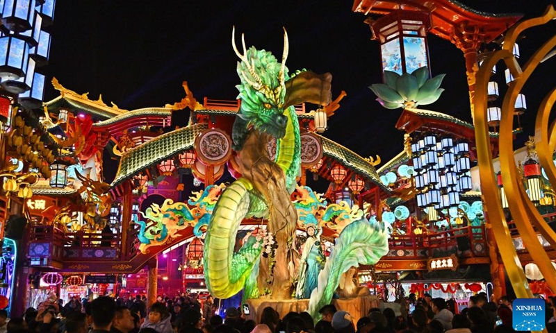 An artist performs at a scenic spot in Chengyang District of Qingdao, east China's Shandong Province, on Feb. 10, 2024. Light installations and stage performances have been arranged here to attract more nighttime visitors during the Spring Festival holiday. (Xinhua/Li Ziheng)