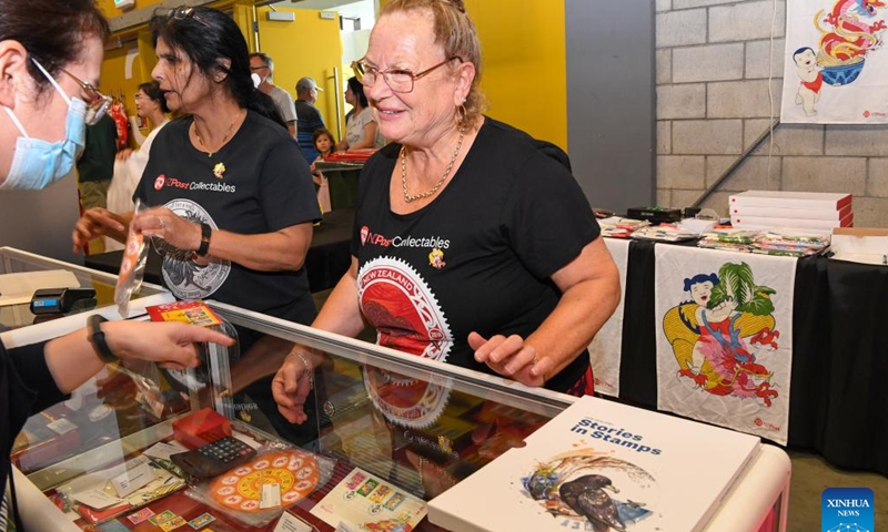 A customer (L) asks about the Year of the Dragon stamps for sale on the Chinese New Year Festival and Market Day in Auckland, New Zealand, Feb. 3, 2024. The Auckland Showgrounds burst forth with color and festivity on Saturday with the opening of the Chinese New Year Festival and Market Day, a signature event that has become a long-cherished tradition for various communities in New Zealand. (Xinhua/Guo Lei)