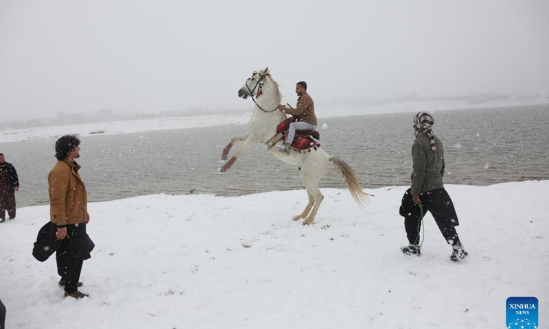 A man rides a horse on snow-covered lakeside in Kabul, capital of Afghanistan, Feb. 3, 2024. (Photo by Saifurahman Safi/Xinhua)