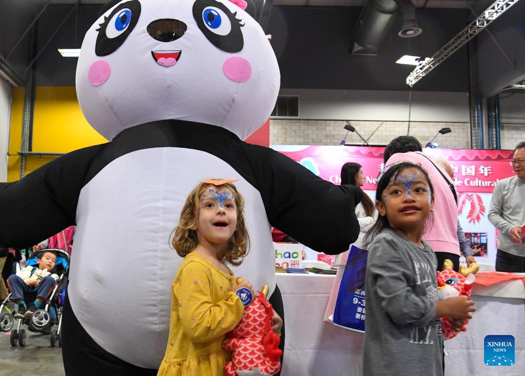 Children walk past a panda figure on the Chinese New Year Festival and Market Day in Auckland, New Zealand, Feb. 3, 2024. The Auckland Showgrounds burst forth with color and festivity on Saturday with the opening of the Chinese New Year Festival and Market Day, a signature event that has become a long-cherished tradition for various communities in New Zealand. (Xinhua/Guo Lei)