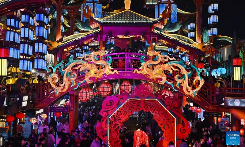 People visit a scenic spot in Chengyang District of Qingdao, east China's Shandong Province, on Feb. 10, 2024. Light installations and stage performances have been arranged here to attract more nighttime visitors during the Spring Festival holiday. (Xinhua/Li Ziheng)