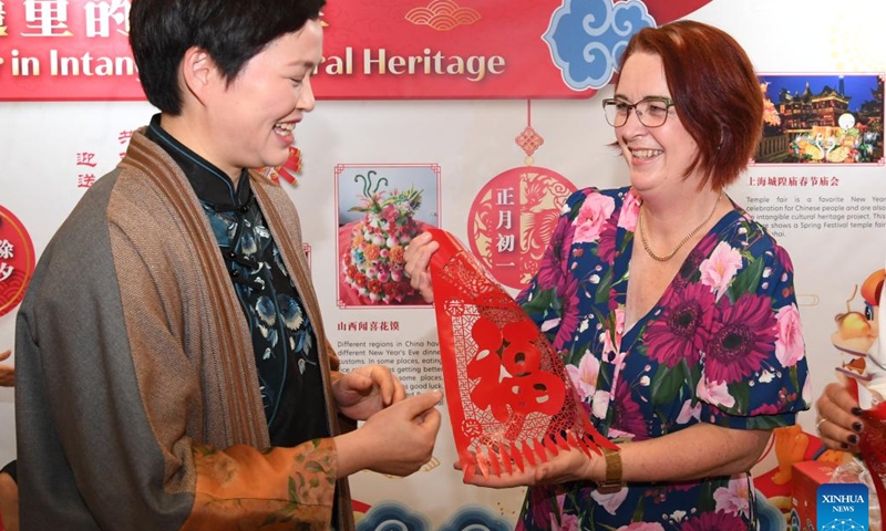 A resident (R) receives a paper-cutting work showing the Chinese character Fu (fortune) on the Chinese New Year Festival and Market Day in Auckland, New Zealand, Feb. 3, 2024. The Auckland Showgrounds burst forth with color and festivity on Saturday with the opening of the Chinese New Year Festival and Market Day, a signature event that has become a long-cherished tradition for various communities in New Zealand. (Xinhua/Guo Lei)