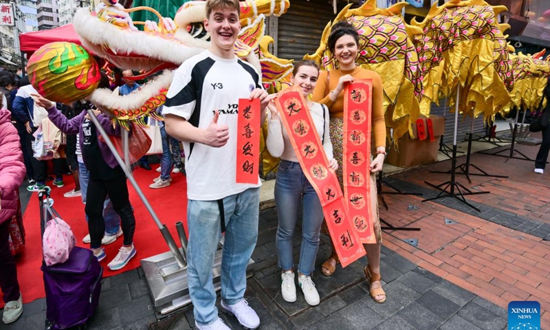 Overseas students pose for photos with Spring Festival couplets during an event celebrating the upcoming Chinese New Year at the Temple Street in south China's Hong Kong, Feb. 4, 2024. (Xinhua/Zhu Wei)