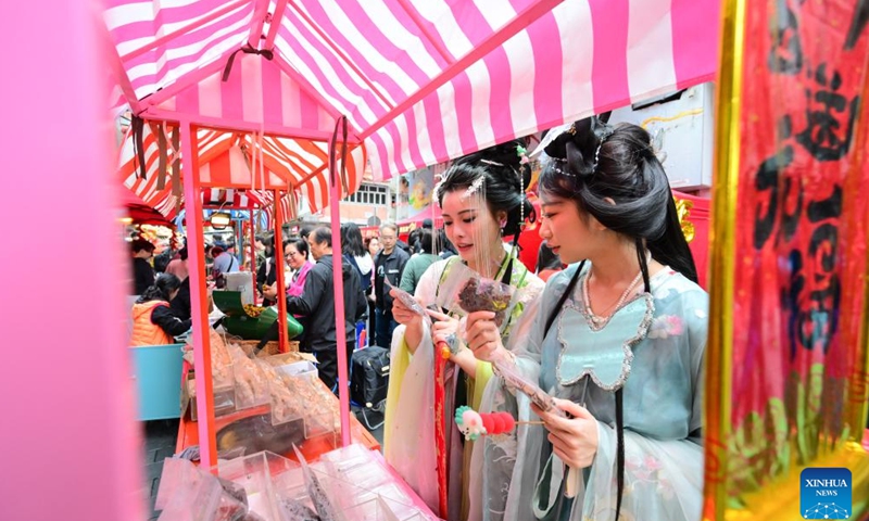 Visitors in Hanfu costumes, a style of clothing traditionally worn by the Han people, select snacks during an event celebrating the upcoming Chinese New Year at the Temple Street in south China's Hong Kong, Feb. 4, 2024. (Xinhua/Zhu Wei)