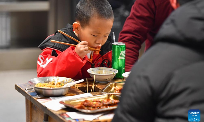 A child dines at a stall in a night market selling street food in Changsha, central China's Hunan Province, Feb. 4, 2024. To attract more visitors, stalls in this night market are making innovations such as developing new products and promoting via social media.(Photo: Xinhua)