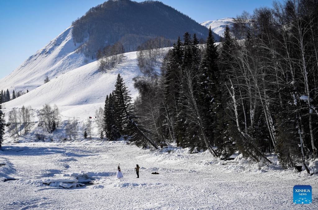 Tourists take photos in Hemu Village in Altay Prefecture, northwest China's Xinjiang Uygur Autonomous Region, Feb. 5, 2024. Tucked away within Altay Prefecture, Hemu Village in Xinjiang offers the perfect winter getaway. As the Spring Festival is approaching, the village has become a hot spot for tourists.(Photo: Xinhua)