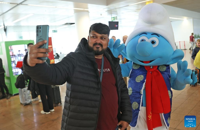 A tourist take selfies with a smurf costumed character wearing traditional Chinese clothes at the Brussels Airport in Zaventem, Belgium, Feb. 9, 2024. The festive atmosphere to welcome the Chinese Lunar New Year fills the air at the Brussels Airport with various celebration activities held here. Photo: Xinhua